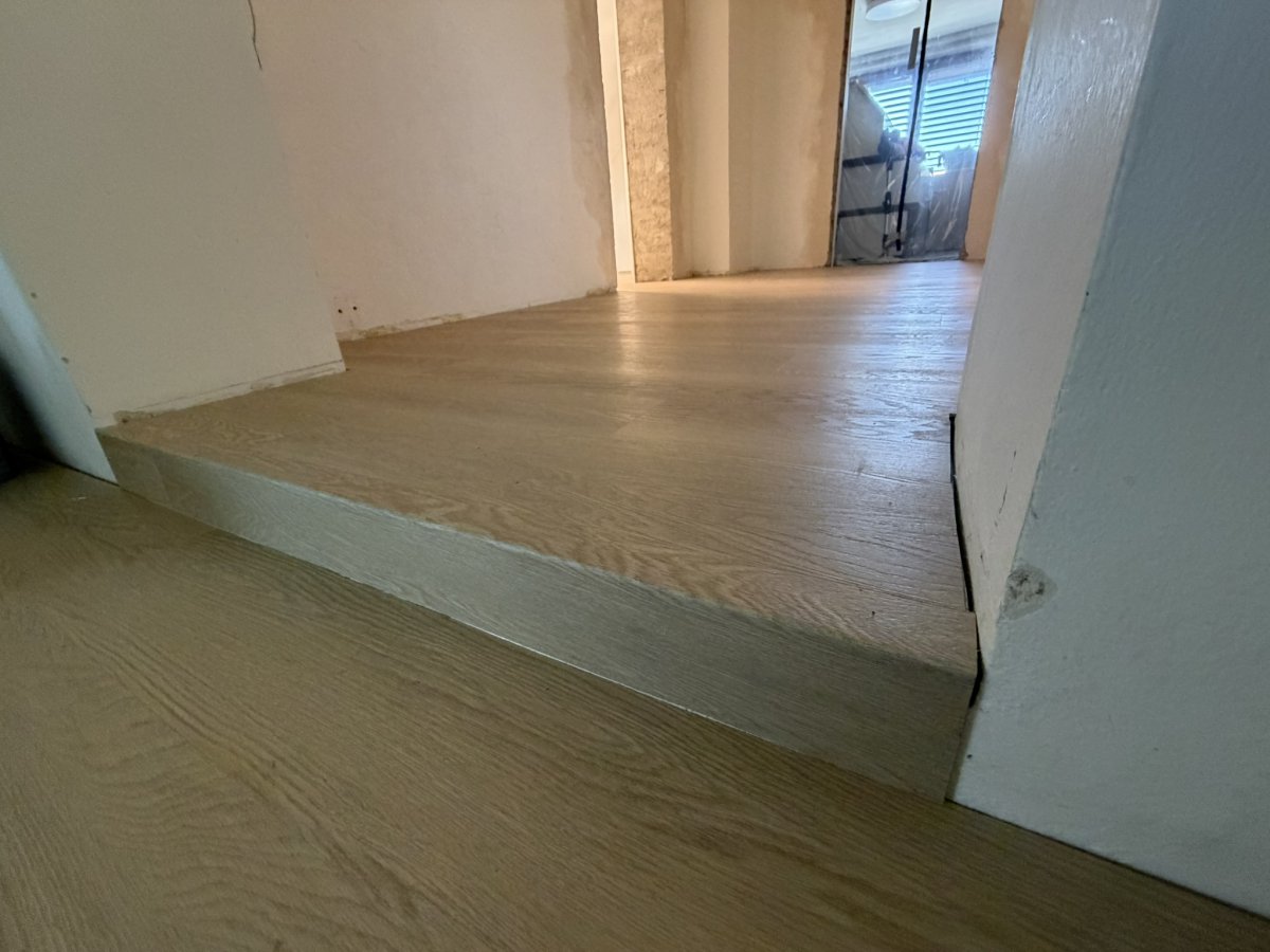 Průchod mezi místnostmi s plynule položenou vinylovou podlahou přes práh