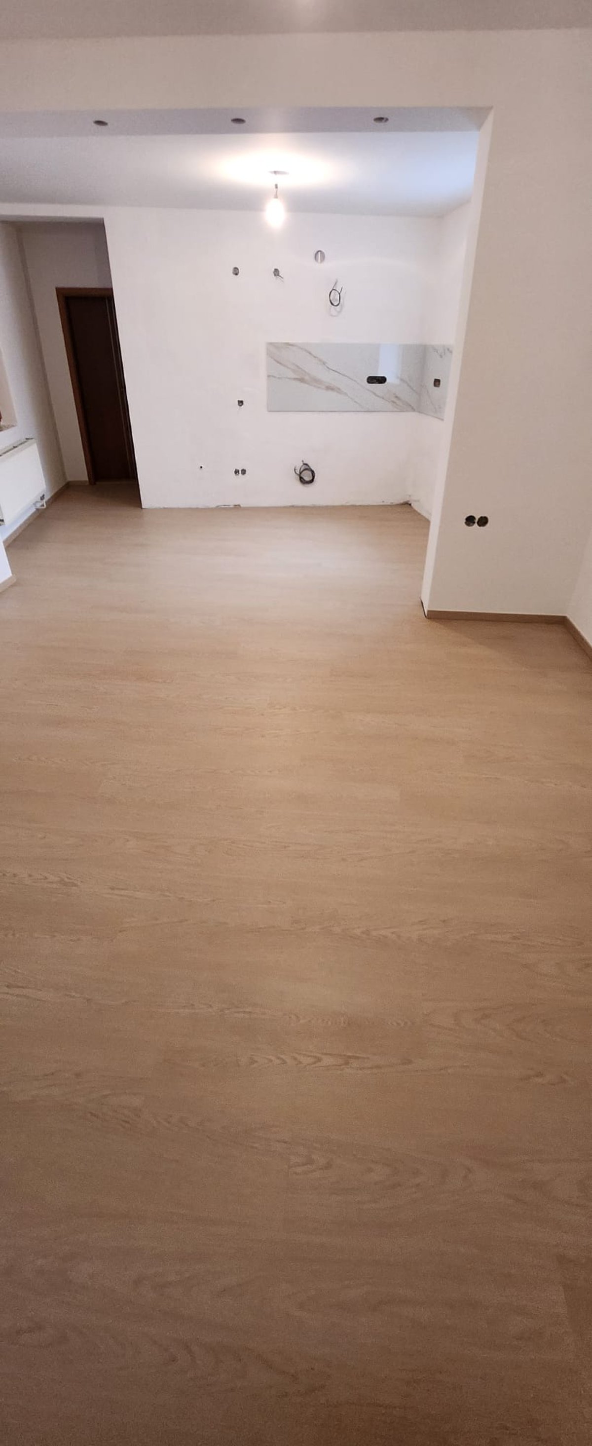 Dokončená vinylová podlaha v obývacím prostoru s kuchyňským koutem, teplý béžový dřevodekor
