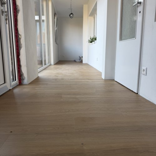 Dokončená lepená vinylová podlaha v dekoru dub královský na verandě, pohled z nízkého úhlu